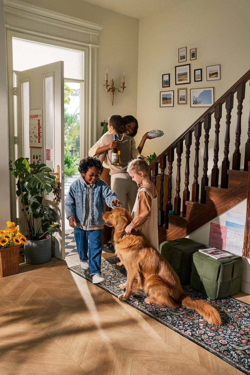 Entryway with wooden herringbone floor, staircase, family, dog, and a patterned Hallway Runner Rug.