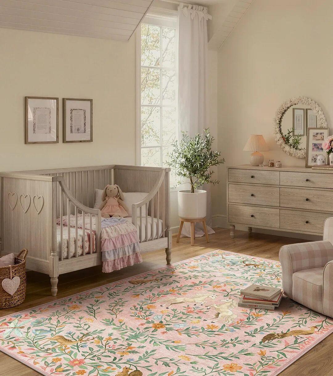 Pink nursery rug with whimsical floral and animal design, near crib and chair